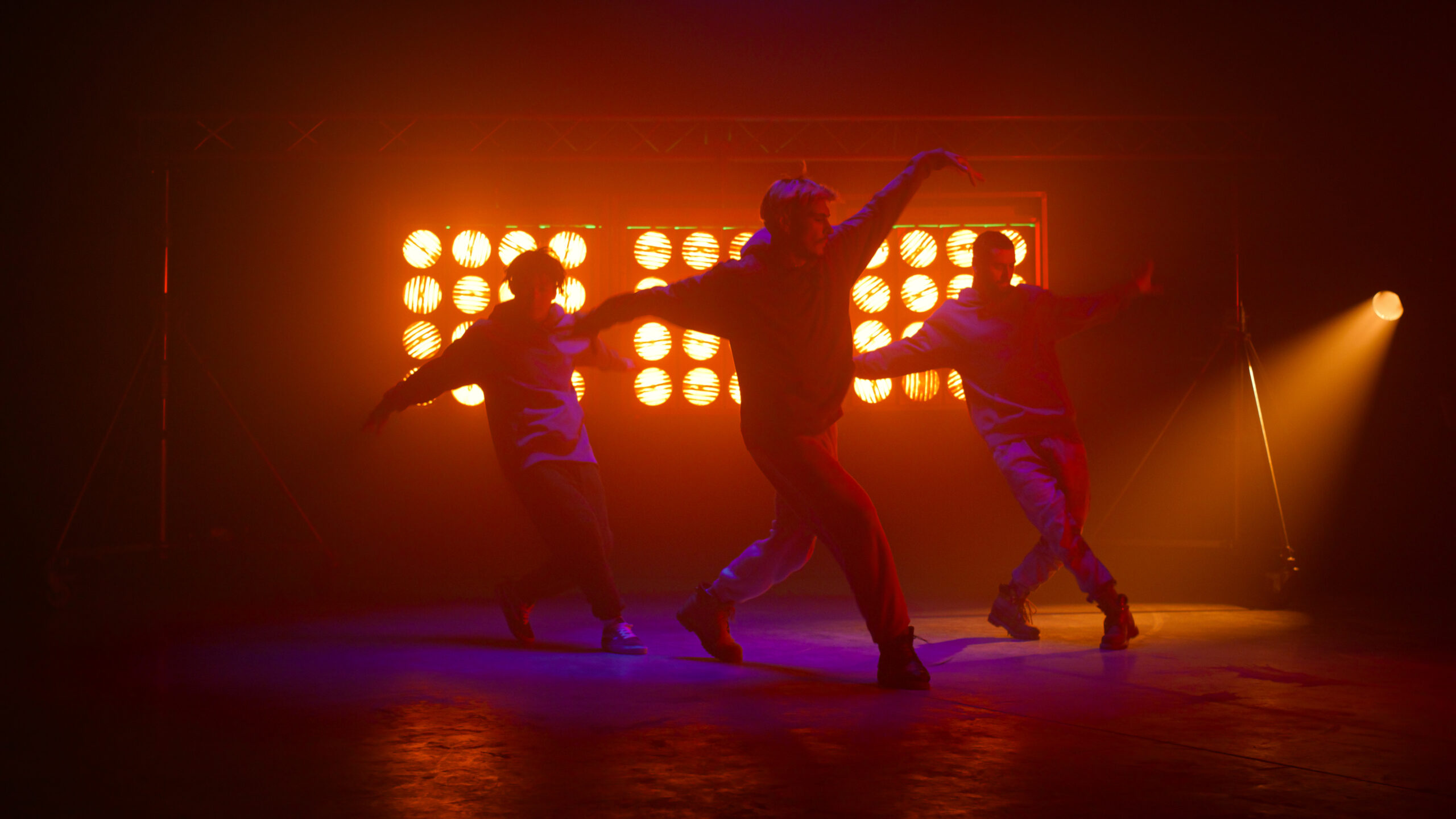 Sporty dancers team showing hiphop moves on night club stage. Dance group performing breakdance show in bright spotlight. Guys performers dancing modern freestyle in club illumination. Party concept.